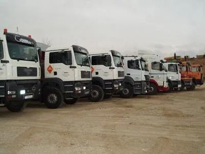 Una fila de camiones están estacionados en un campo de tierra.