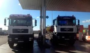 Dos camiones están estacionados uno al lado del otro en una gasolinera.