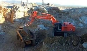 Una excavadora grande está cargando un camión volquete con rocas.