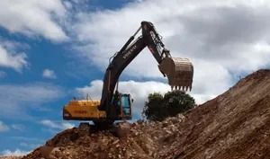 Una gran excavadora está sentada encima de una pila de tierra.