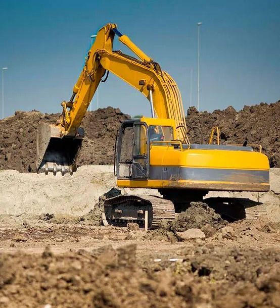 Una excavadora amarilla está cavando en un montón de tierra.