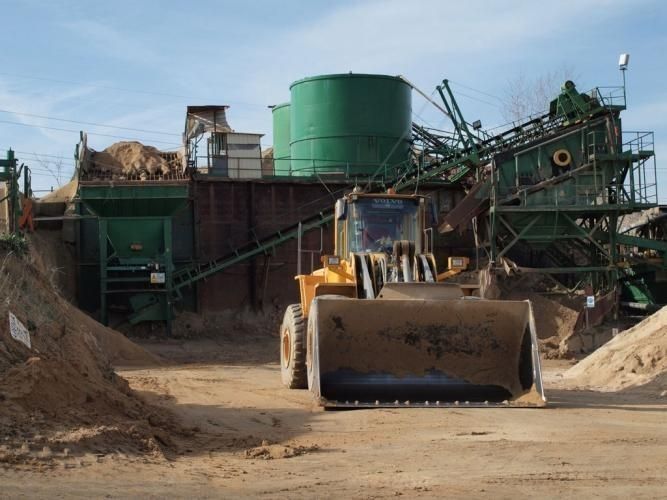 Una excavadora está estacionada frente a un montón de tierra.