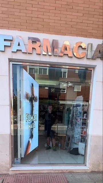 Un hombre está parado frente a una farmacia.
