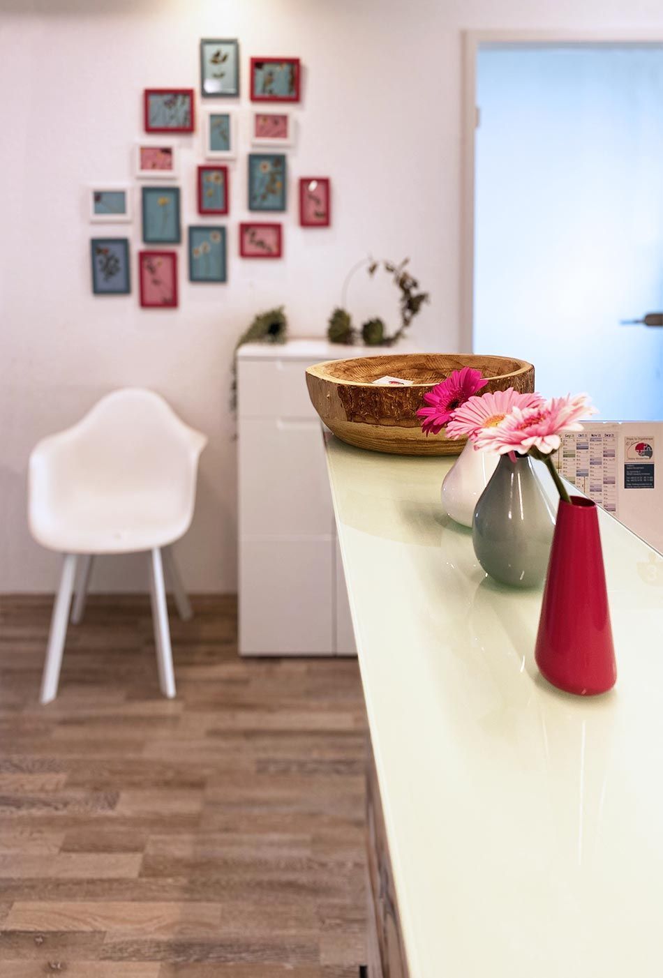 Ein Wartezimmer mit einem weißen Stuhl und einer Vase mit Blumen auf der Theke