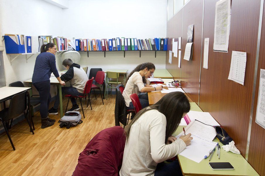 Un grupo de personas están sentadas en escritorios en una habitación.