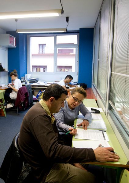 Un hombre y una mujer están sentados en un escritorio en un aula.
