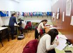 Un grupo de personas están sentadas en escritorios en un aula.