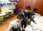 Un grupo de niños están sentados en mesas en un aula.