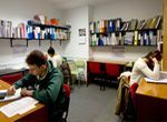 Un hombre y una mujer están sentados en una mesa en una biblioteca.