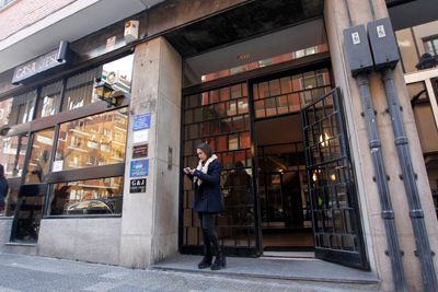 Una mujer está parada frente a un edificio mirando su teléfono.
