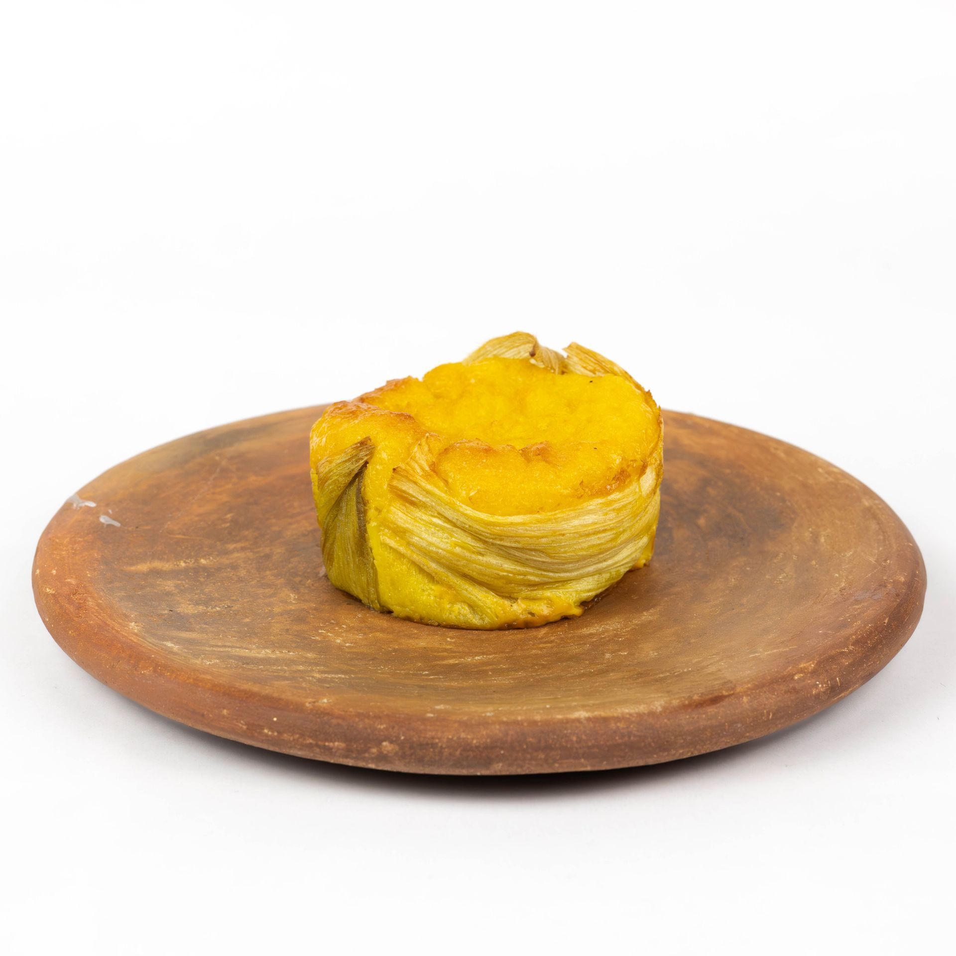 Pastel de capas amarillas sobre un plato de madera sobre un fondo blanco.