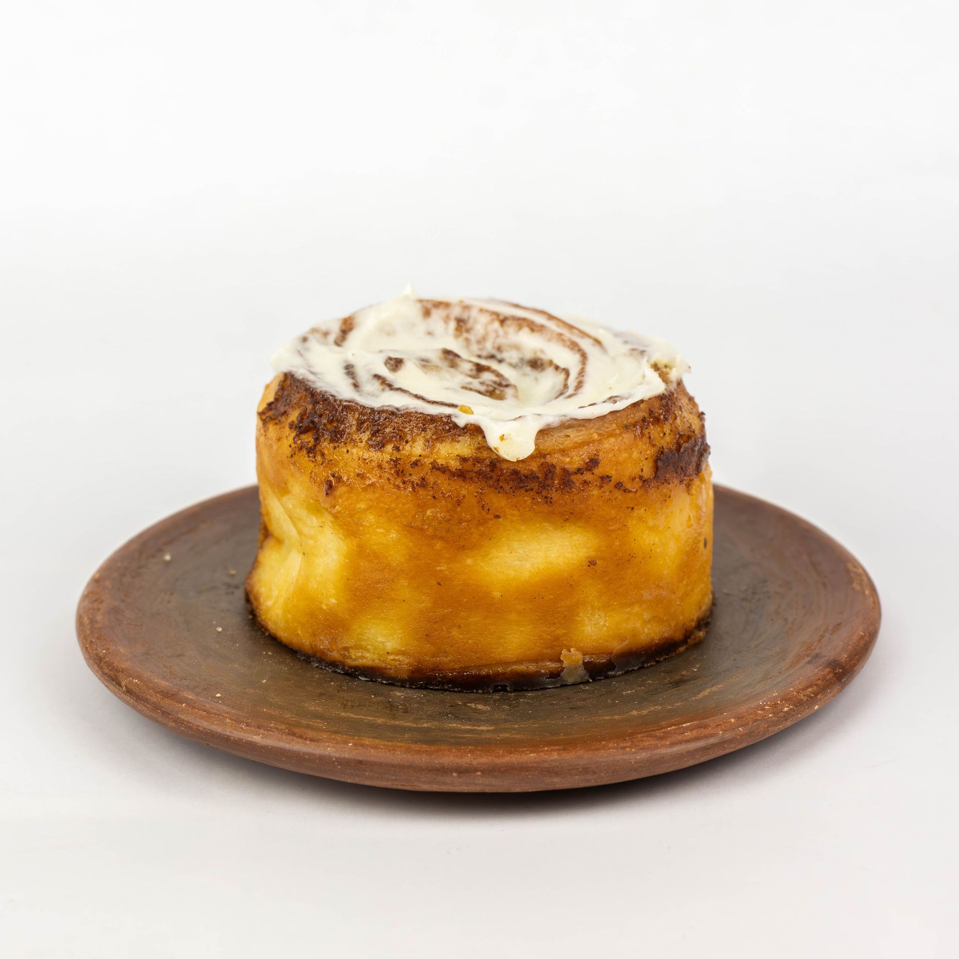 Un rollo de canela en un plato marrón sobre un fondo blanco.