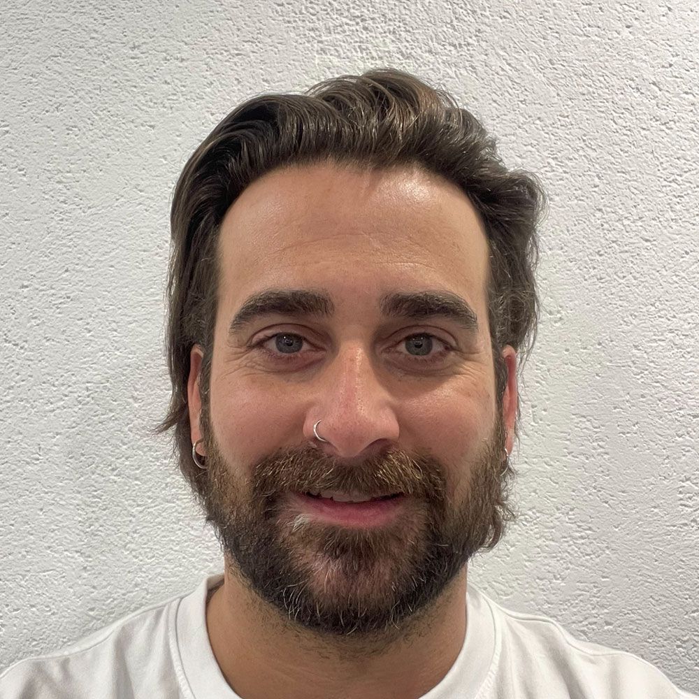 Ein Mann mit Bart und Nasenring lächelt in die Kamera.