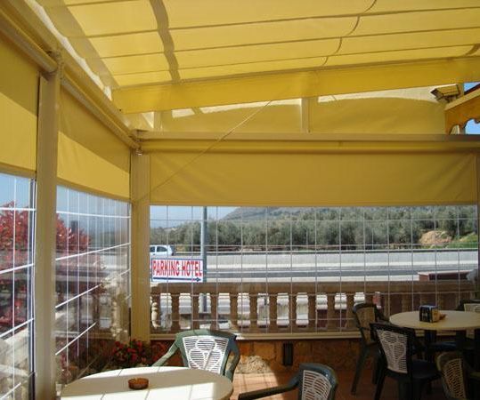 Un restaurante con mesas y sillas bajo un toldo amarillo.