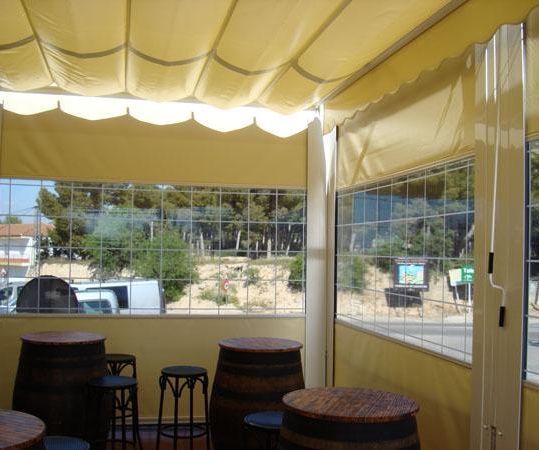 Una sala con mesas y barriles bajo un dosel.