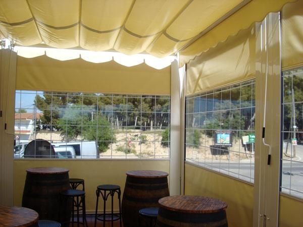 Una sala con mesas y barriles bajo un dosel.