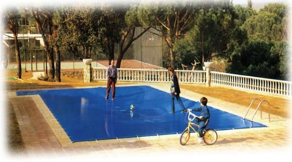 Un niño está montando en bicicleta en una piscina con una cubierta azul.