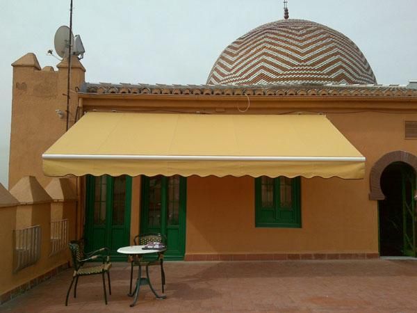 Un toldo amarillo cubre una mesa y sillas afuera de un edificio.