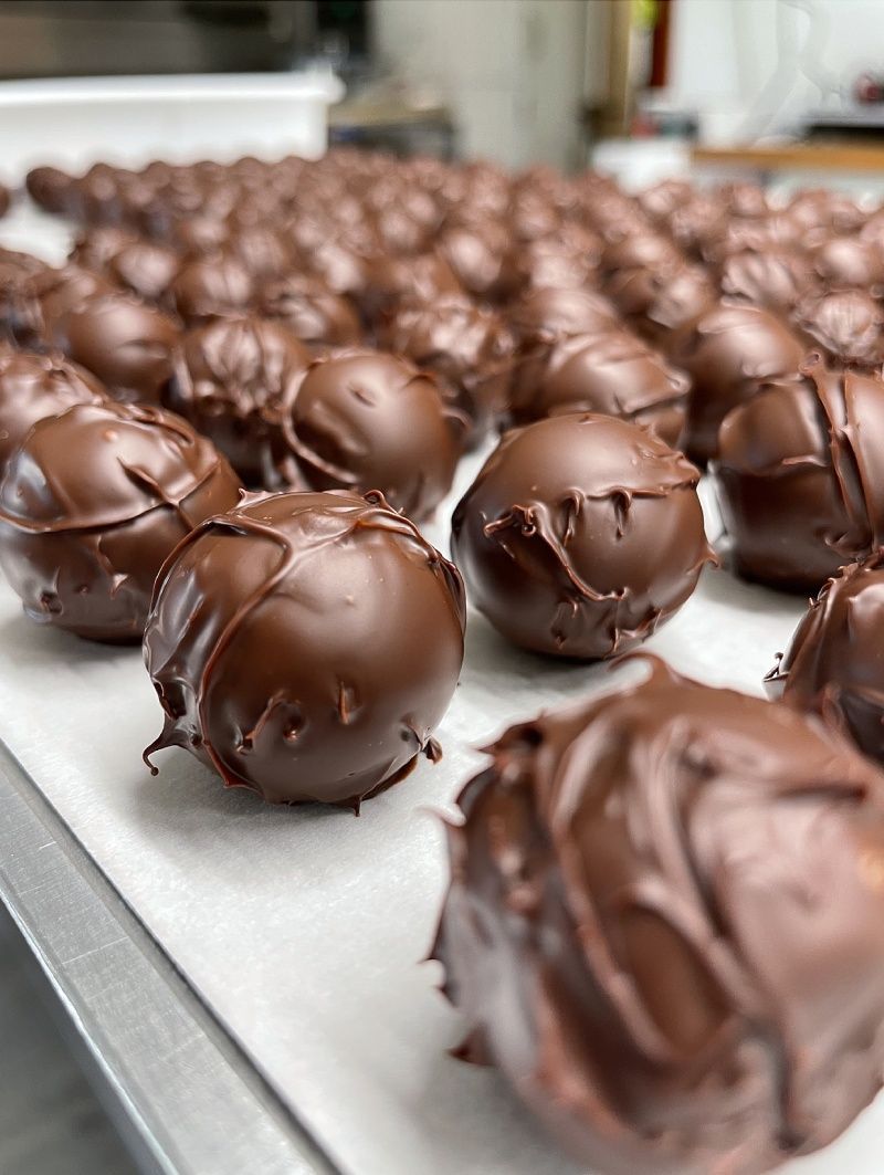 Un tas de boules enrobées de chocolat sont posées sur une table.