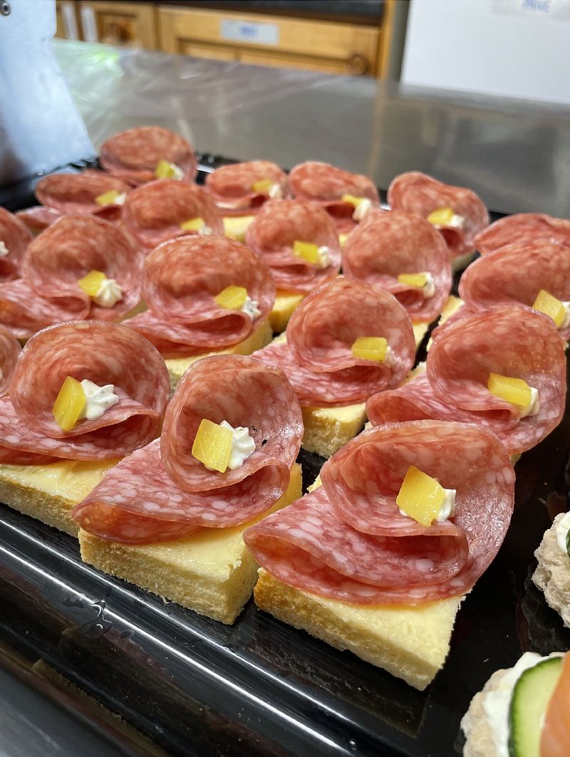 Un plateau de sandwichs avec du salami et du fromage sur une table.
