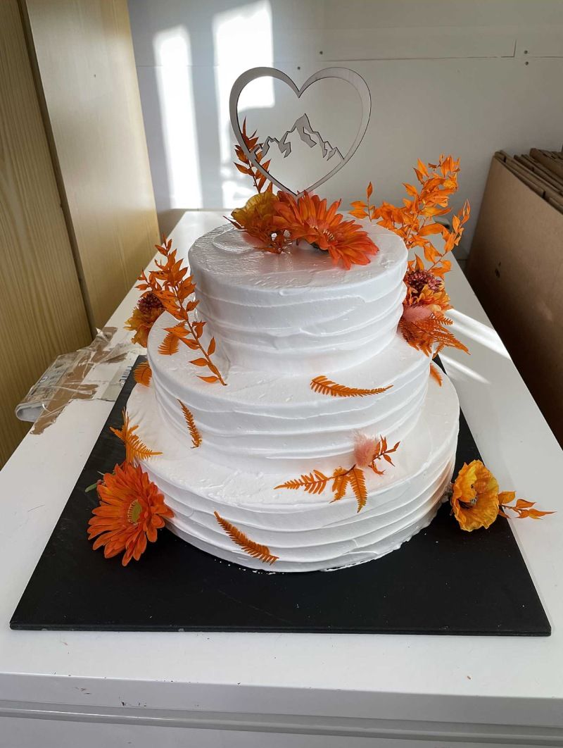 Un gâteau de mariage blanc avec des fleurs orange et un cœur sur le dessus