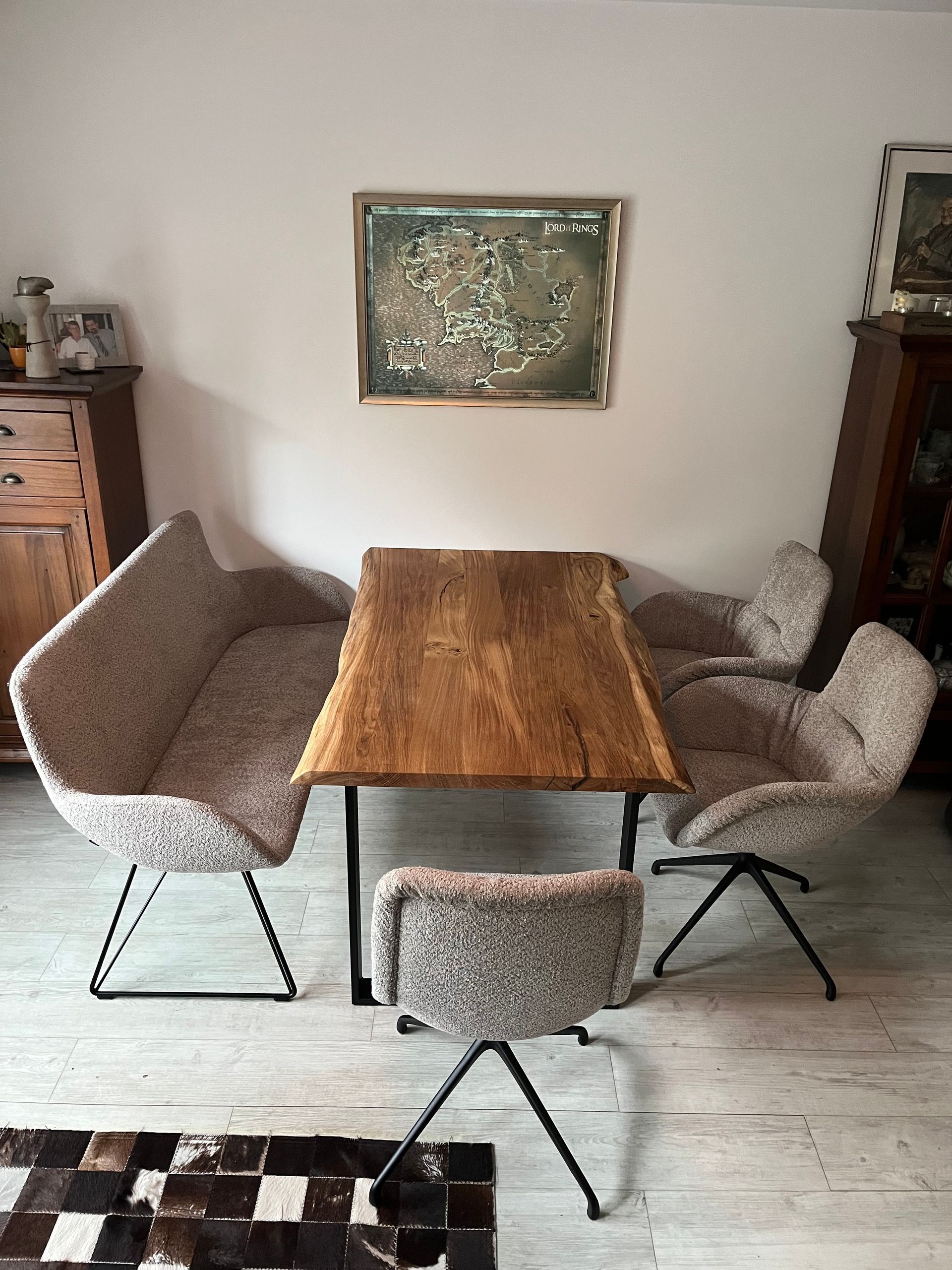 Esszimmer mit Holztisch, beigen Sesseln, Kunstwerken und einem Teppich.