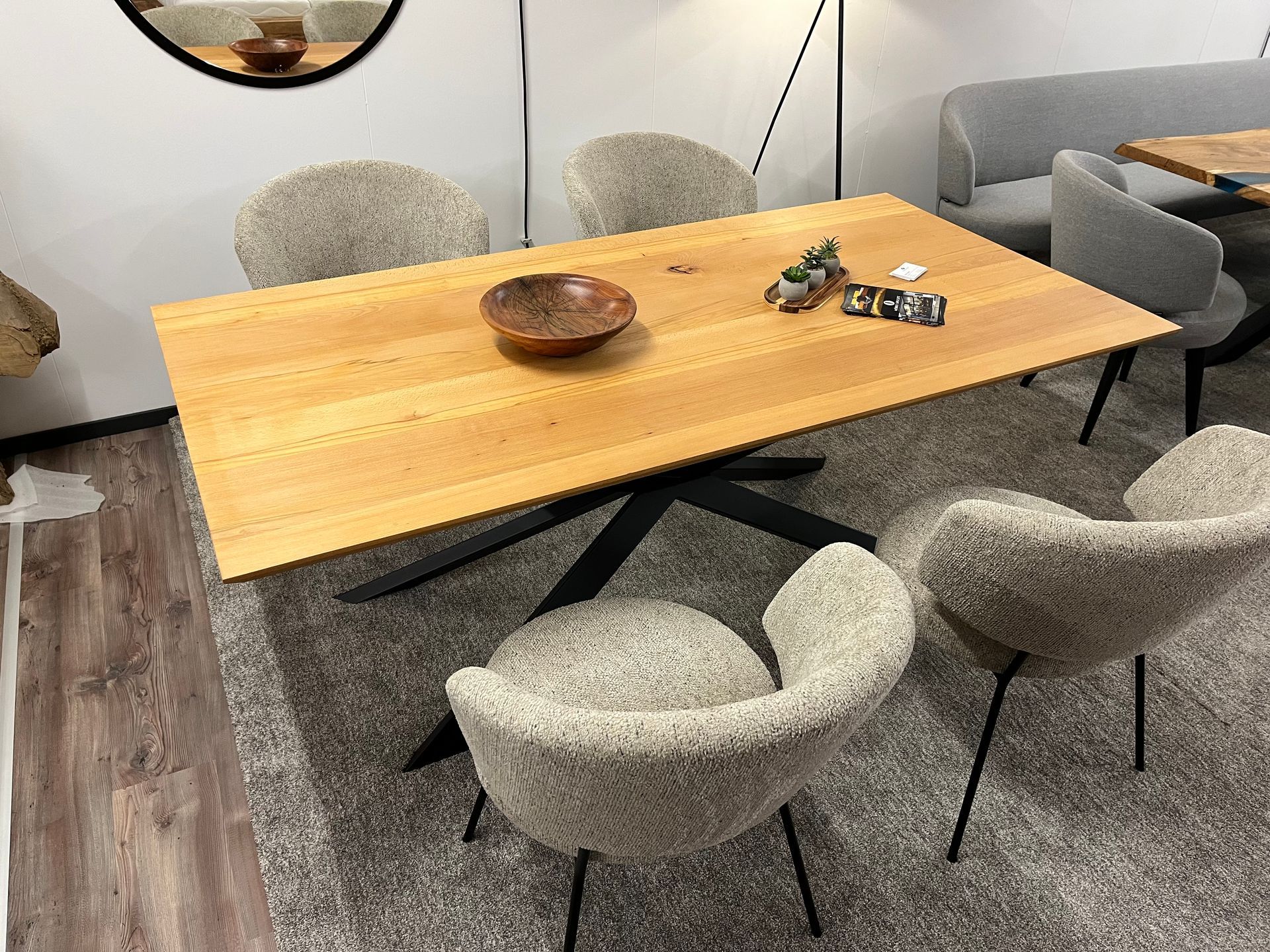 Esszimmer mit einem hellen Holztisch, schwarzem Metallgestell und vier strukturierten grauen Stühlen.