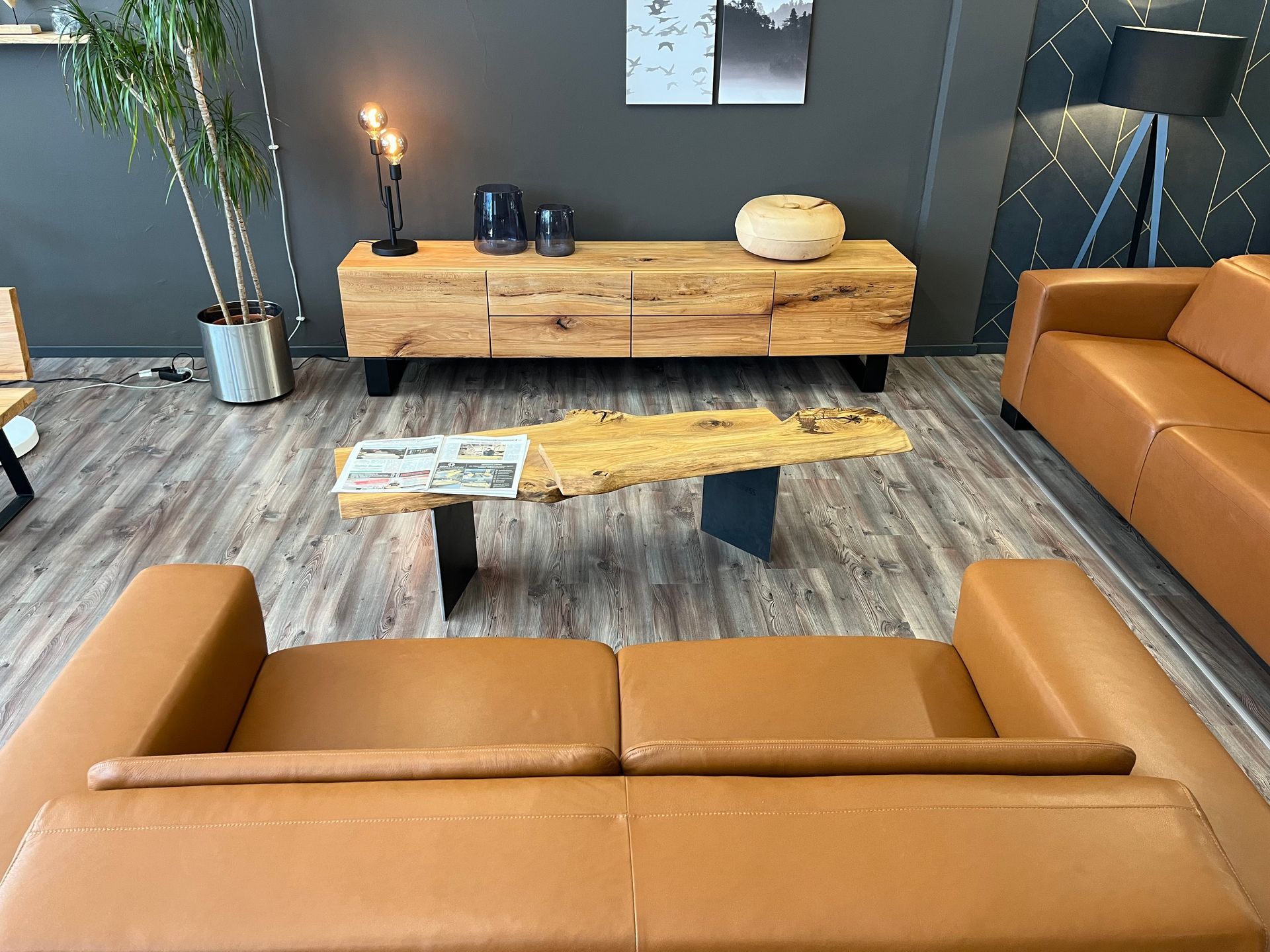 Ein Wohnzimmer mit einem langen handgefertigten Naturholz-Epoxidharztisch und blau gepolsterten Stühlen