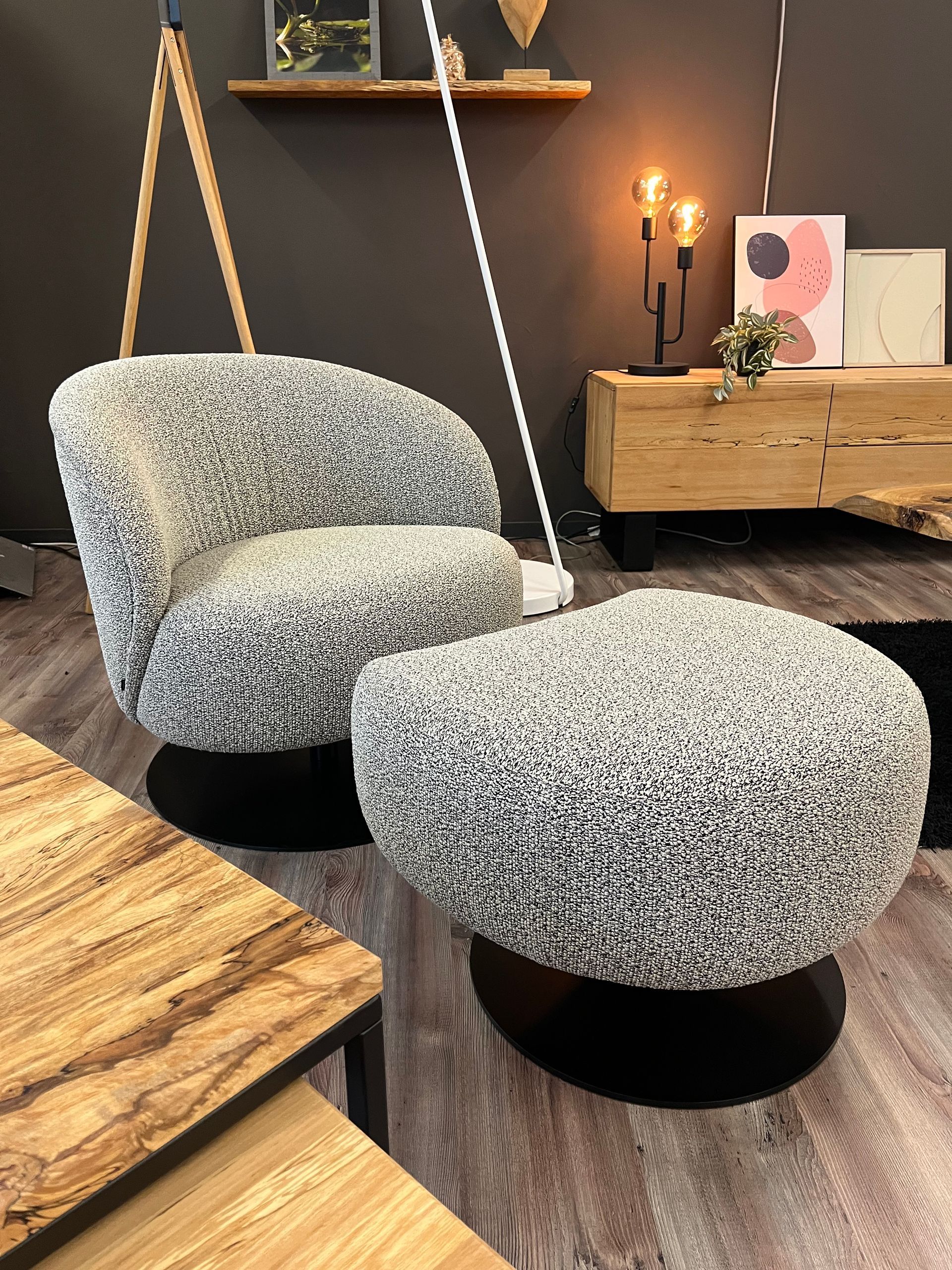 Drehsessel und passender Hocker mit gesprenkeltem grauen Stoffbezug auf schwarzem Gestell in einem modernen Raum.