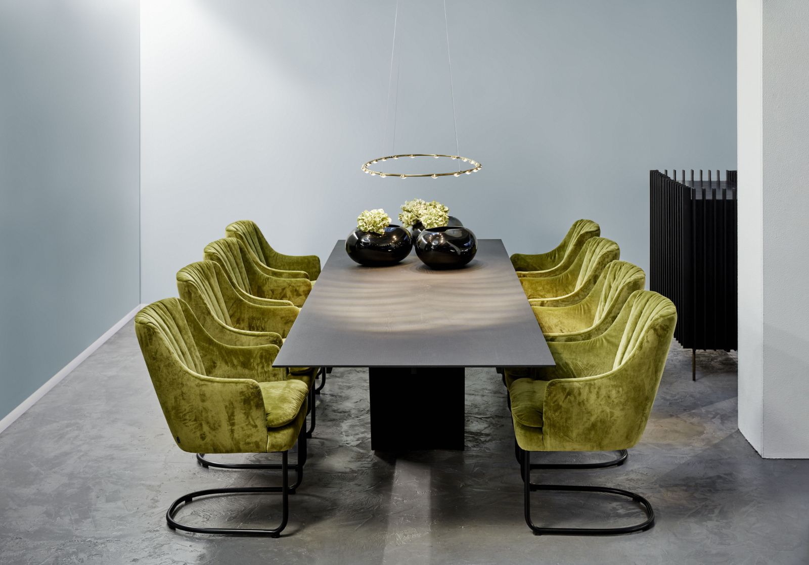 Ein Esszimmer mit einem langen Tisch und grünen Stühlen.