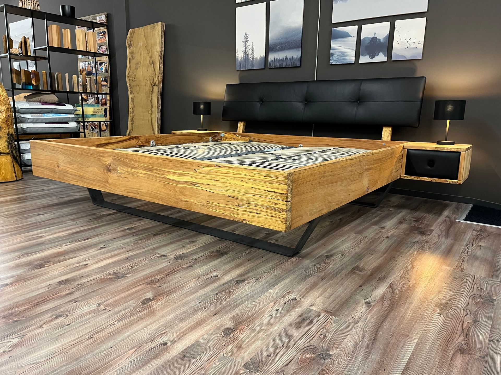 Plattformbett aus Holz mit schwarzem Kopfteil und schwebendem Nachttisch.