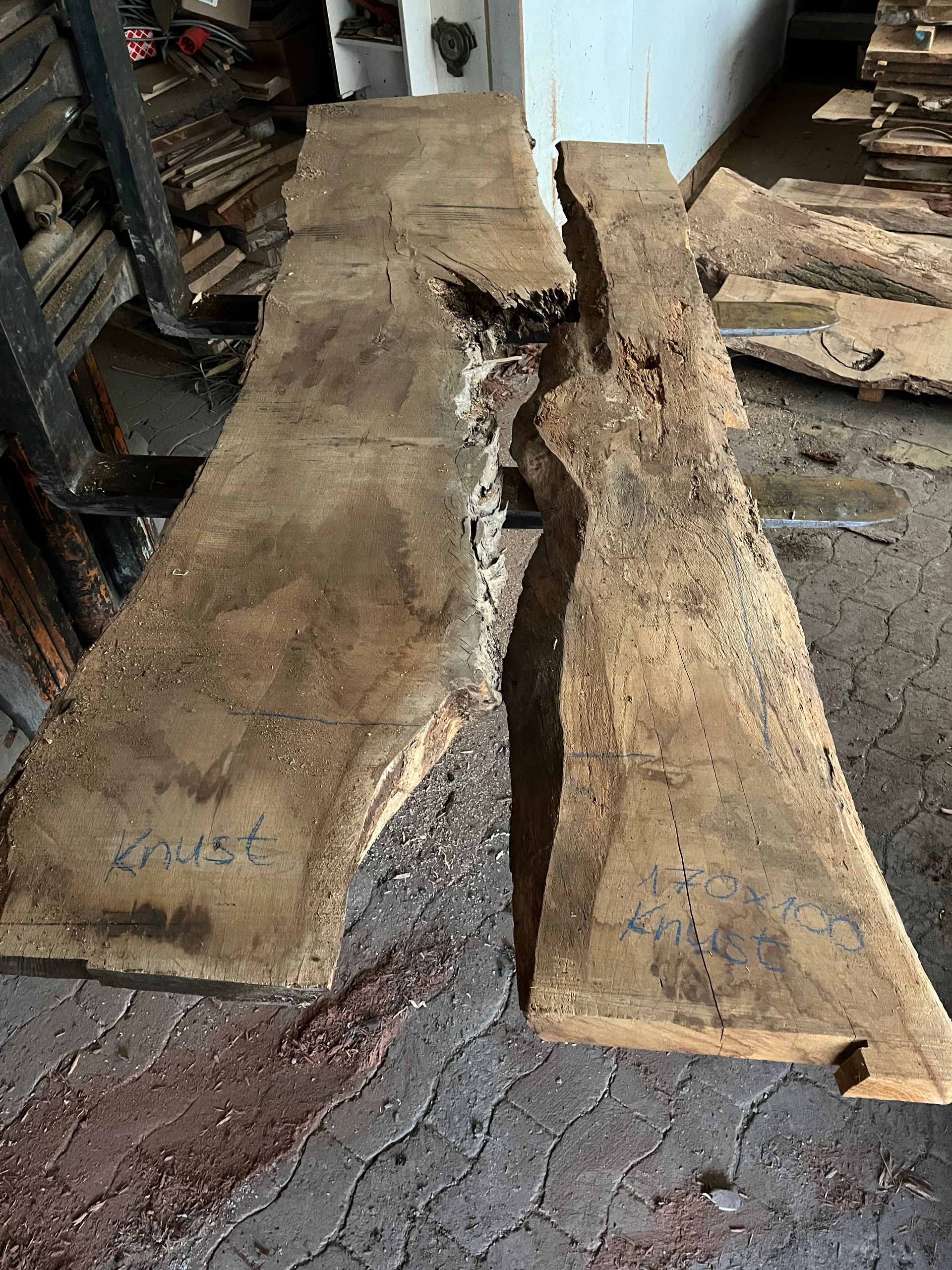 Auf einem Ziegelboden liegt ein großes Stück Holz, bereit zur Weiterverarbeitung.