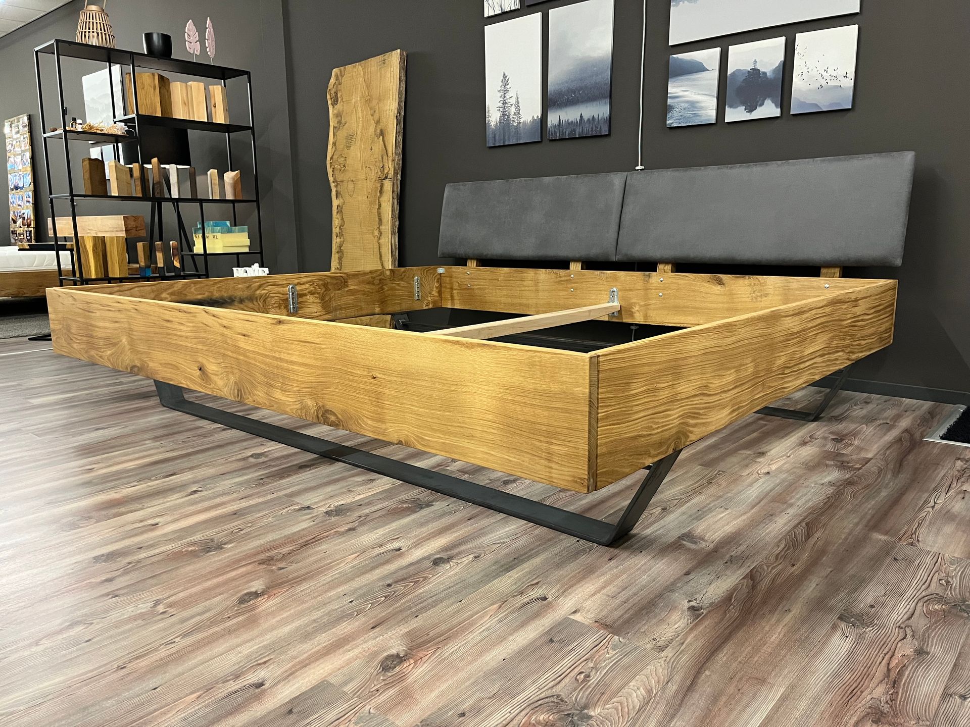 In einem Zimmer steht ein hölzerner Bettrahmen auf einem Holzboden.