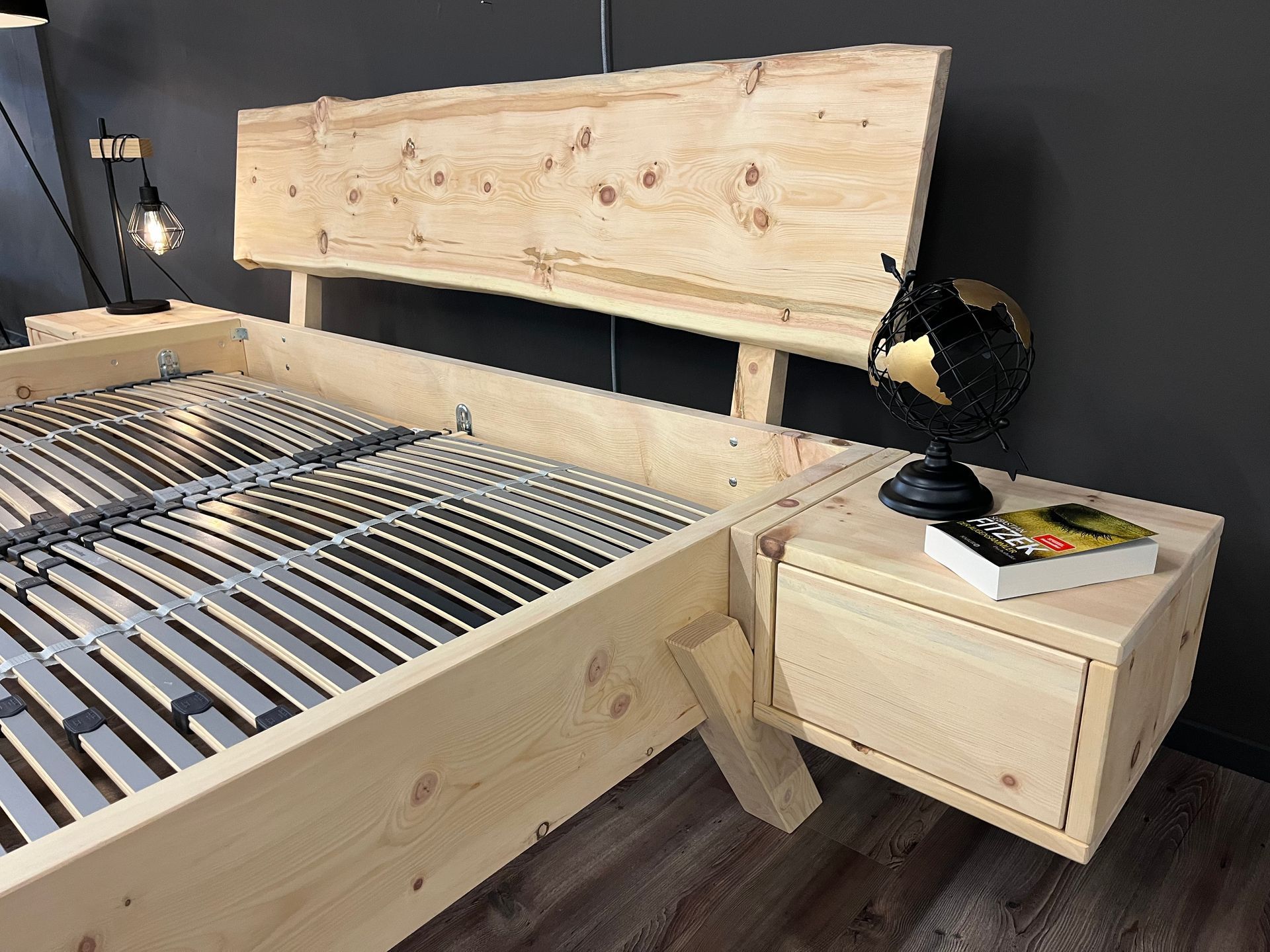 Ein Holzbett mit einem Nachttisch und einem Globus darauf