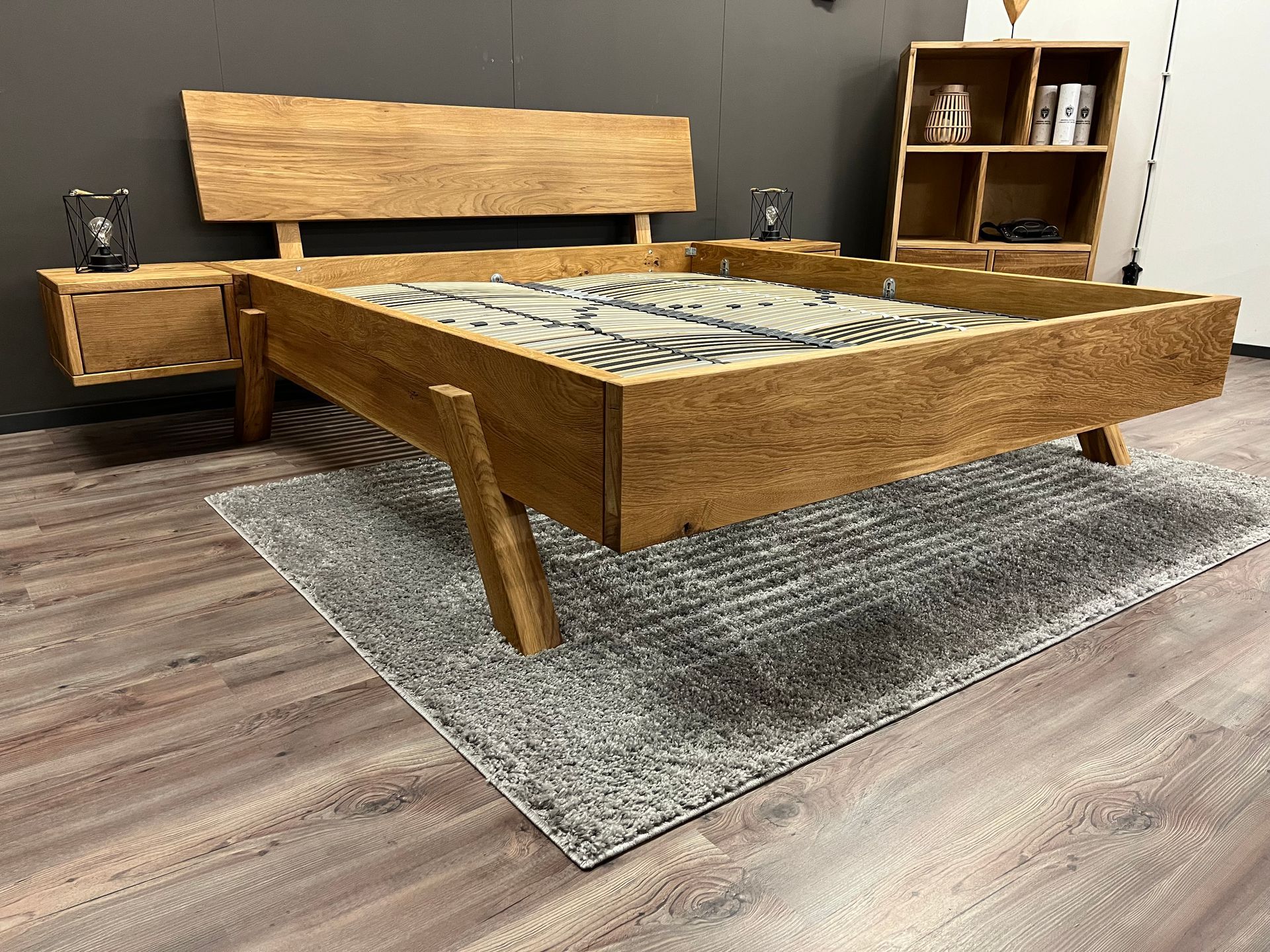 In einem Schlafzimmer steht ein Holzbett auf einem Teppich.