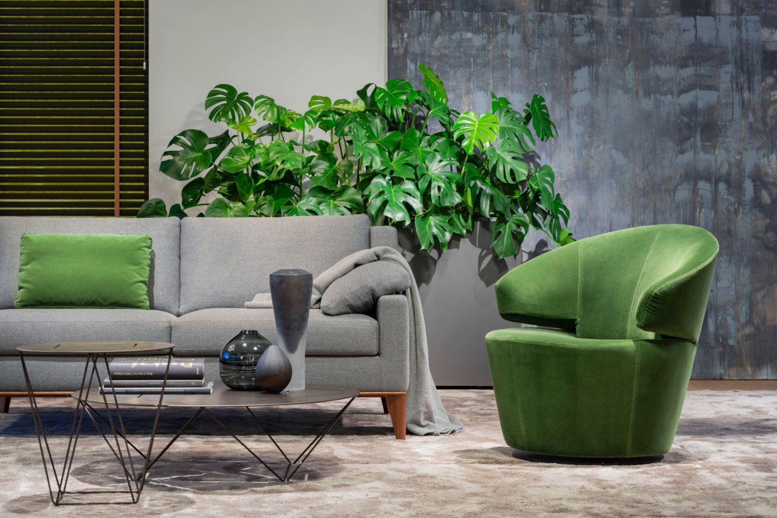 Ein Wohnzimmer mit Sofa, Sessel, Couchtisch und Pflanze.