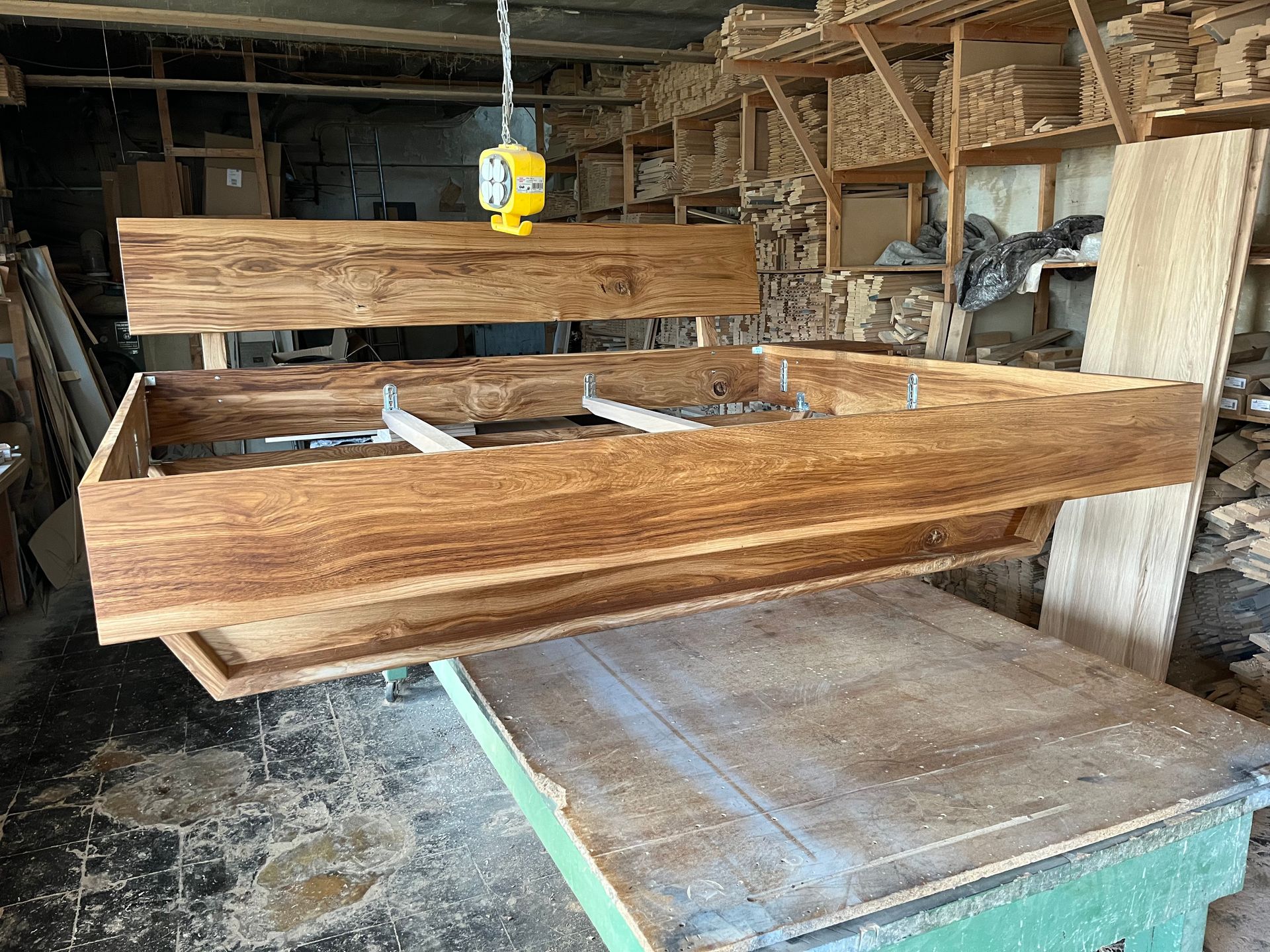 In einer Werkstatt steht eine Bettgestell auf einem Holztisch.