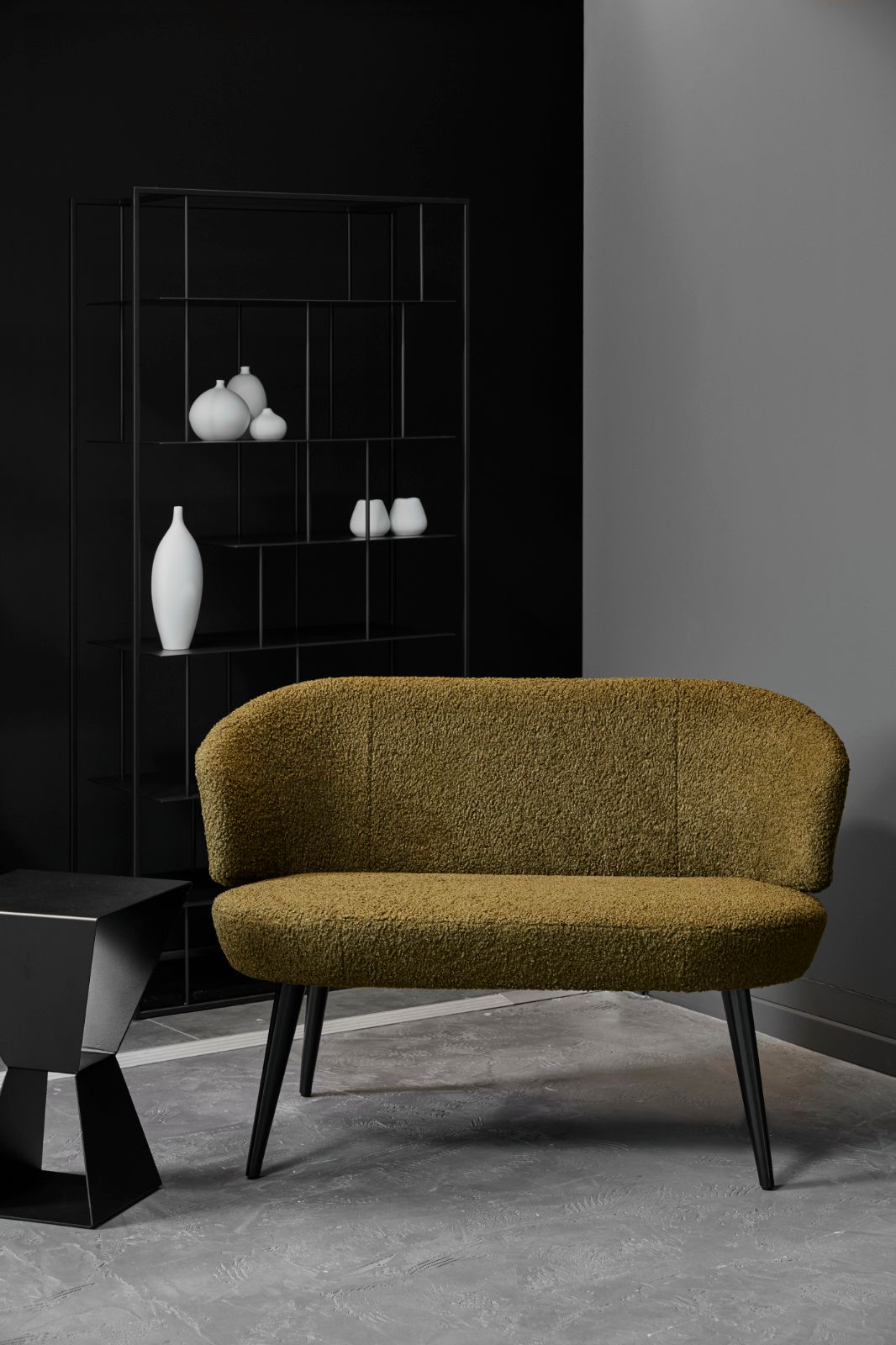 In einem Wohnzimmer steht ein grünes Sofa neben einem Tisch.