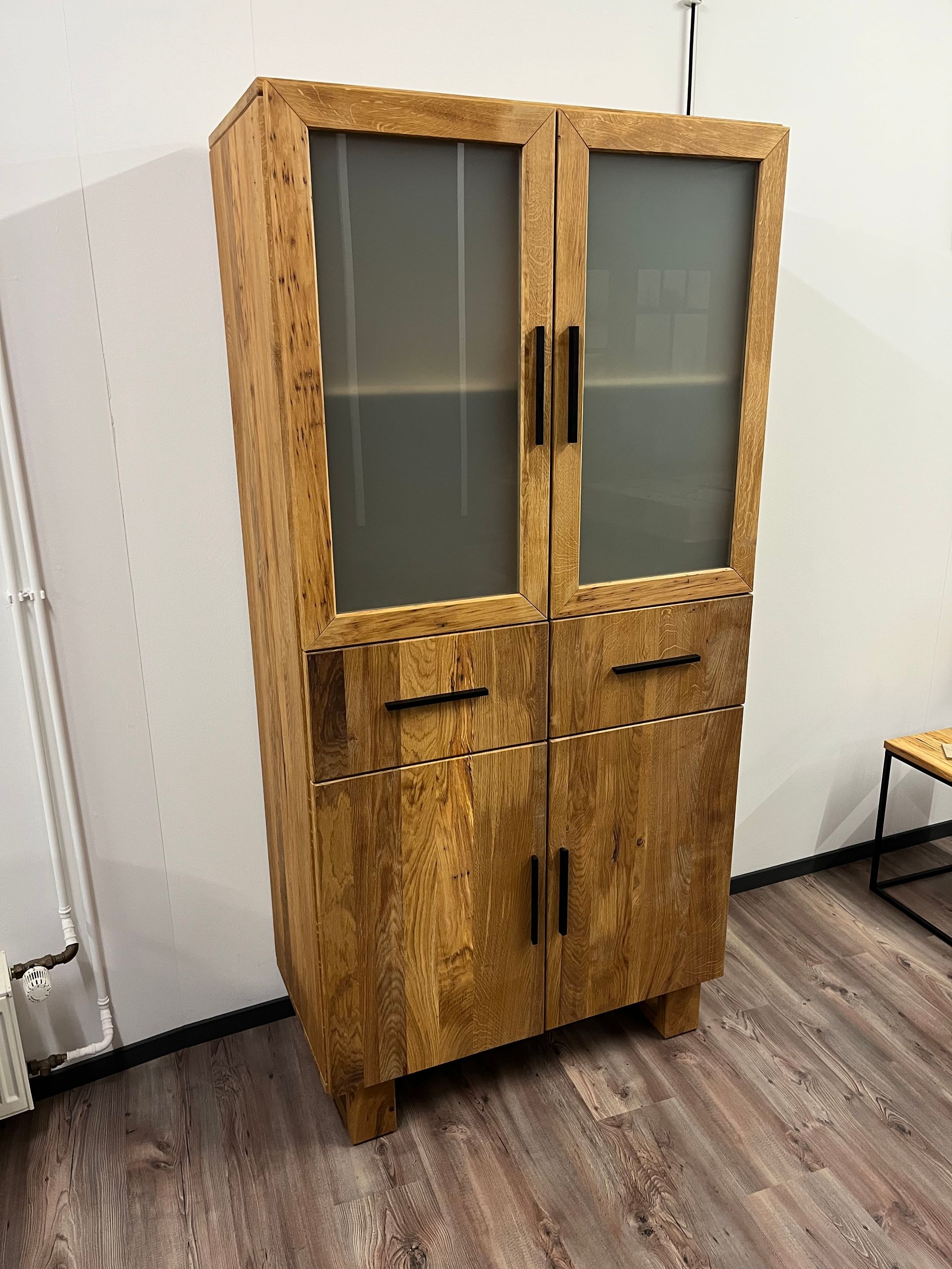 Hoher Holzschrank mit Milchglastüren und Schubladen in einer Büroecke
