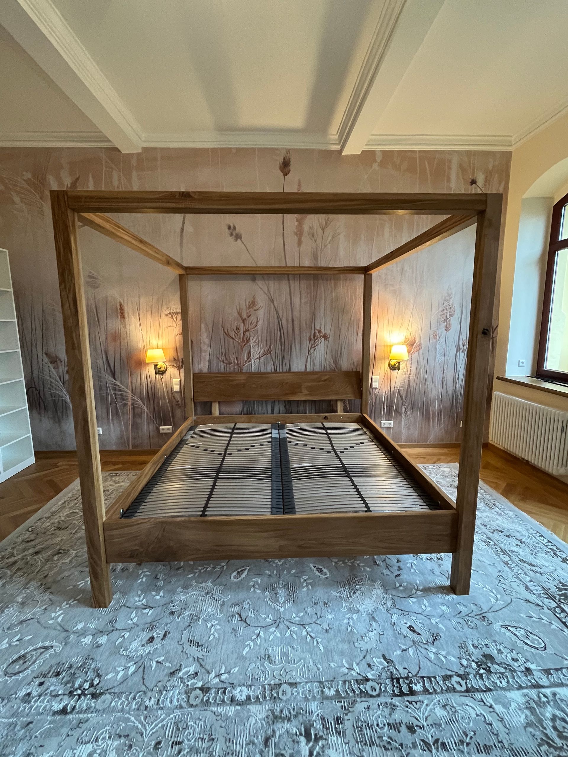 In einem Schlafzimmer steht ein Himmelbett aus Holz auf einem Teppich.