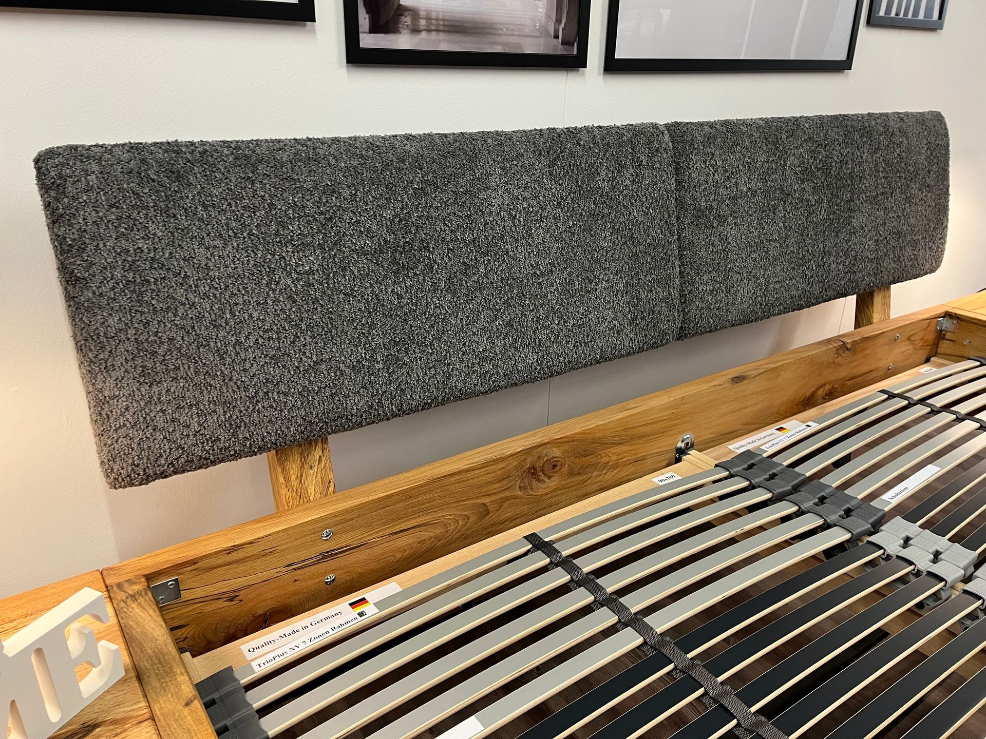 Ein Bett mit grauem Kopfteil und Holzrahmen.