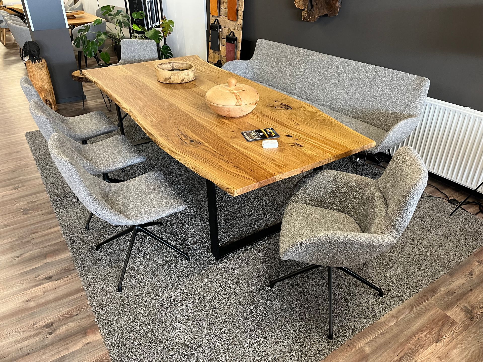 Holzesstisch mit Bank und Stühlen auf einem grauen Teppich.