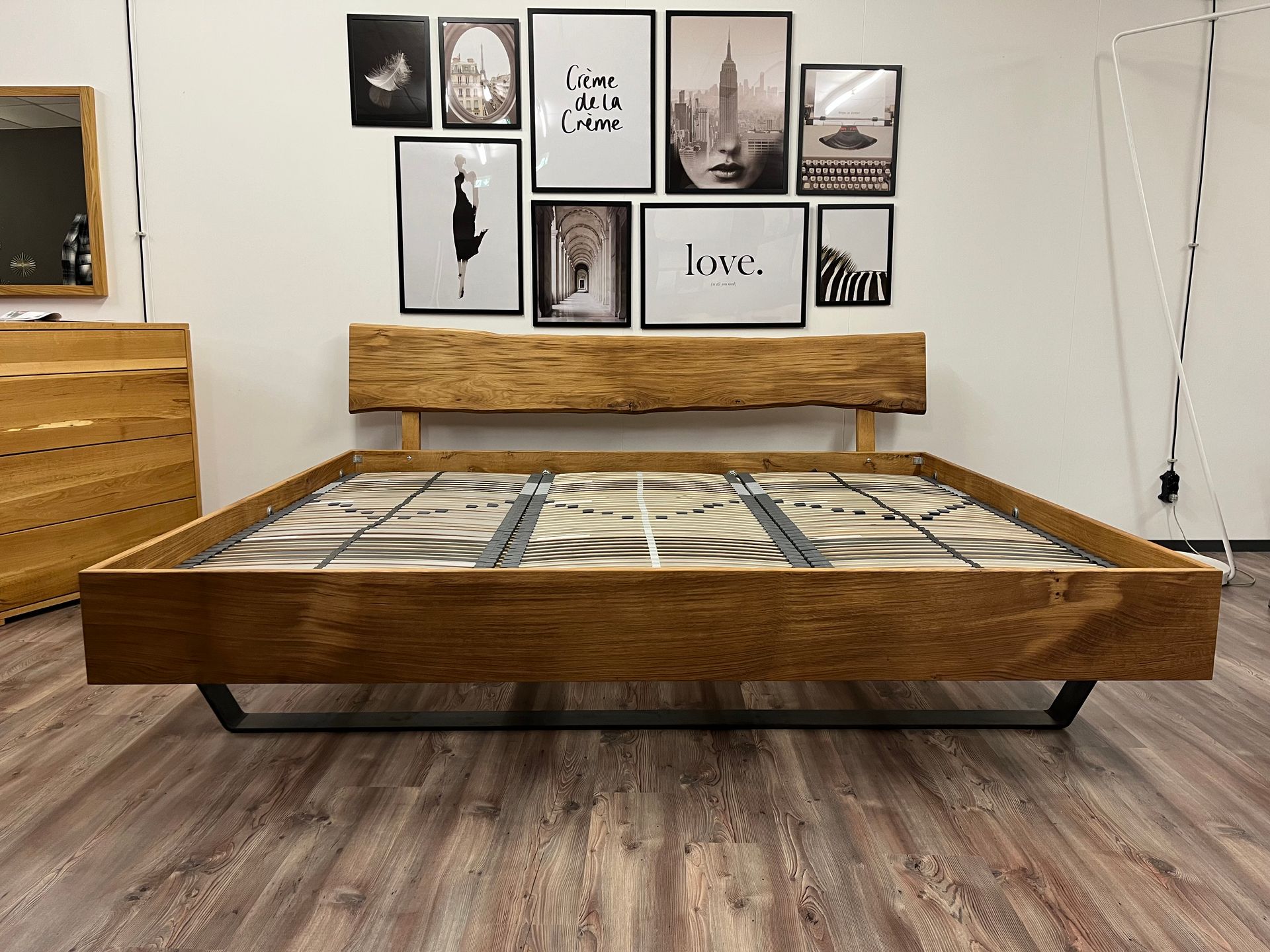 Vor einer Wand mit Bildern steht ein Holzbett.