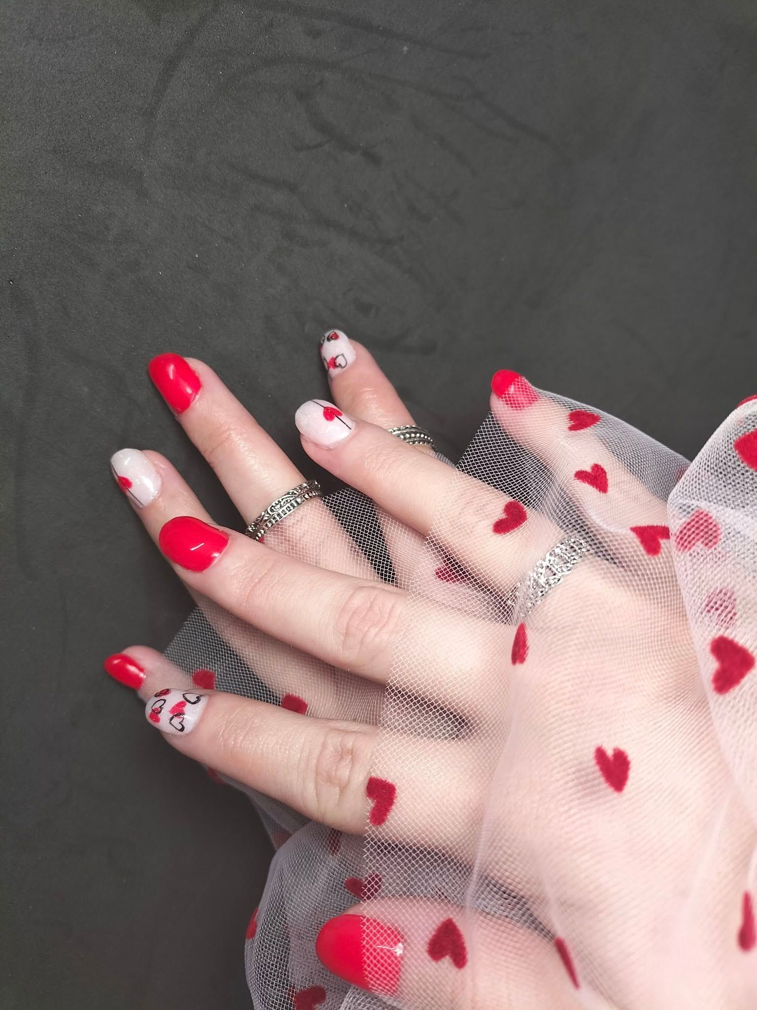 Un primer plano de las uñas de una persona con corazones rojos en ellas.