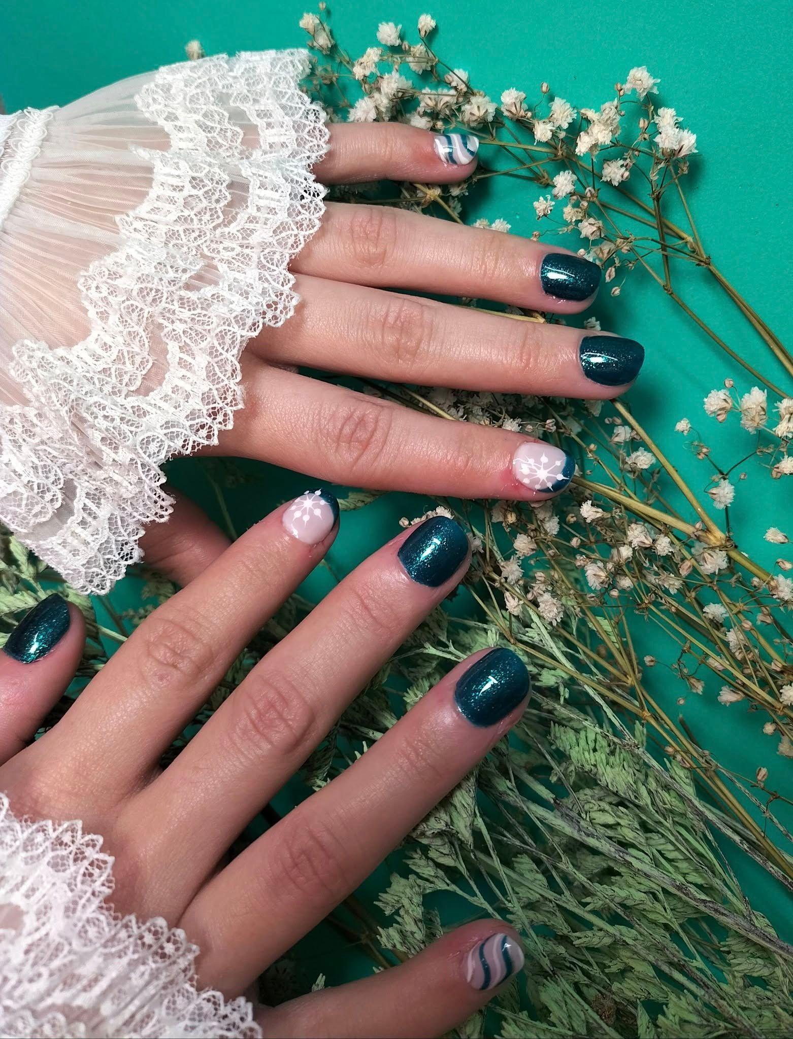 Las uñas de una mujer están pintadas de azul y blanco y lleva un guante de encaje blanco.