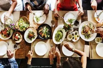 Eine Gruppe Leute sitzt an einem Tisch und isst. Restaurant Ambiente