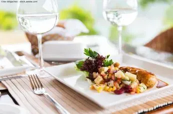 Ein Teller mit Essen und ein Glas Wein auf einem Tisch. Restaurant Ambiente