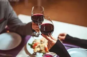 Ein Mann und eine Frau stoßen an einem Tisch mit Weingläsern an. Restaurant Ambiente