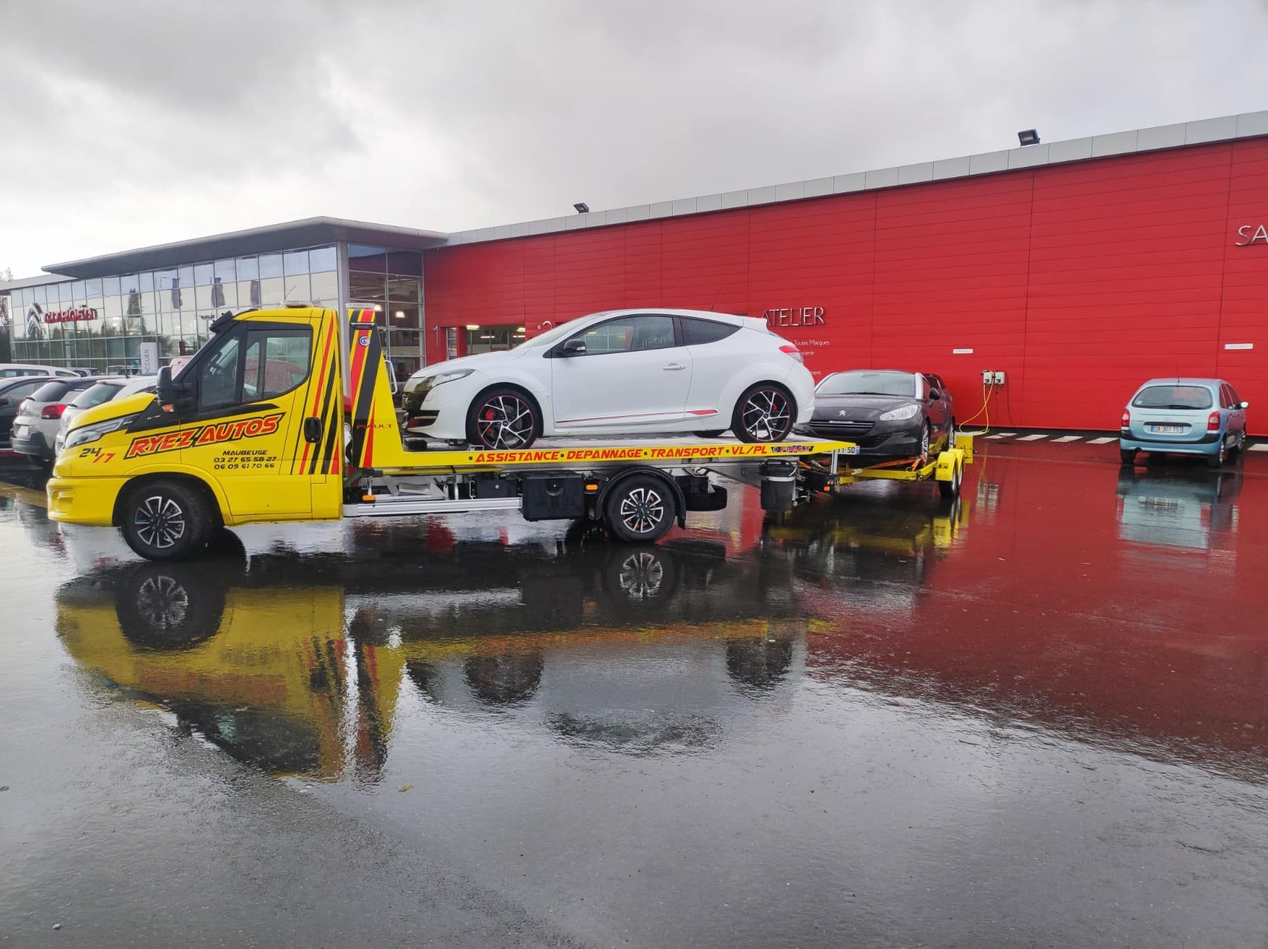 Une dépanneuse avec une voiture blanche sur son plateau
