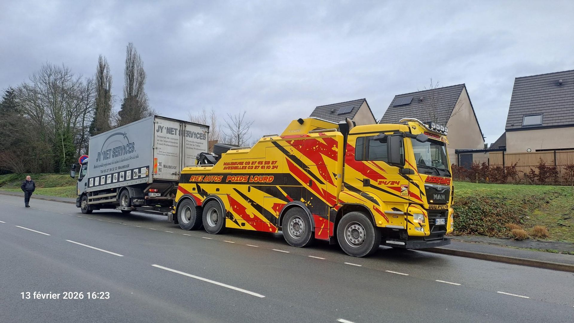 Un poids lourd qui se fait remorquer par une dépanneuse jaune et rouge